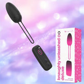 The B Swish Bnaughty Unleashed Deluxe Wireless Remote-Controlled Bullet Vibrator by B Swish is displayed in black beside its pink and white packaging on a soft purple and blue background.